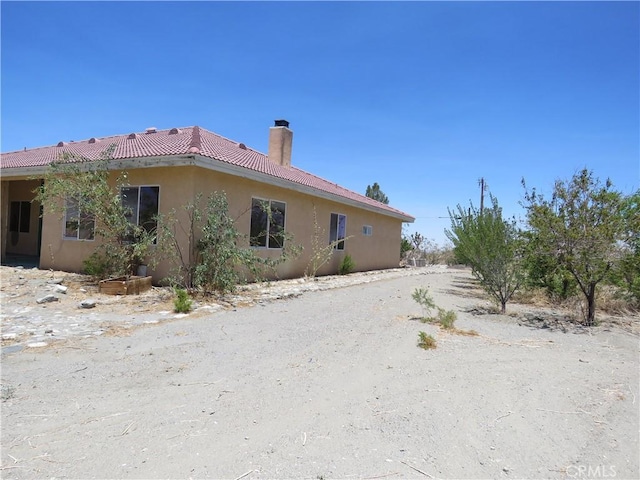 2425 Tokay Rd, Phelan, CA 92371 - view of property exterior with a chimney, a tiled roof, and stucco siding