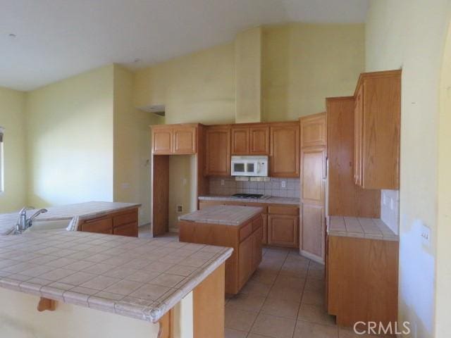 2425 Tokay Rd, Phelan, CA 92371 - kitchen with white microwave, a kitchen island, decorative backsplash, and tile countertops
