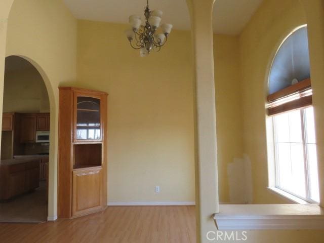 2425 Tokay Rd, Phelan, CA 92371 - unfurnished dining area with healthy amount of natural light, light wood-style flooring, a chandelier, and arched walkways