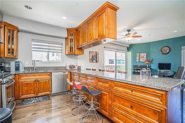 1026 S Oxford Ave Unit 206, Los Angeles, CA 90006 - kitchen featuring appliances with stainless steel finishes, brown cabinets, a ceiling fan, stone counters, and recessed lighting