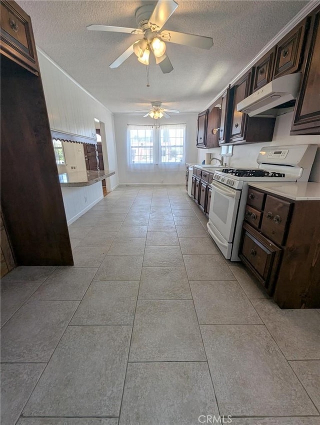891 W Elberon Ave, San Pedro, CA 90731 - kitchen with white gas stove, under cabinet range hood, a textured ceiling, and dark brown cabinetry