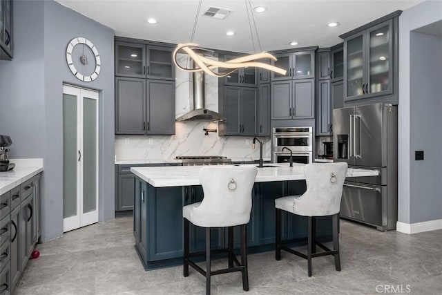 185 Alabaster Loop, Perris, CA 92570 - kitchen with appliances with stainless steel finishes, an island with sink, tasteful backsplash, a breakfast bar area, and hanging light fixtures