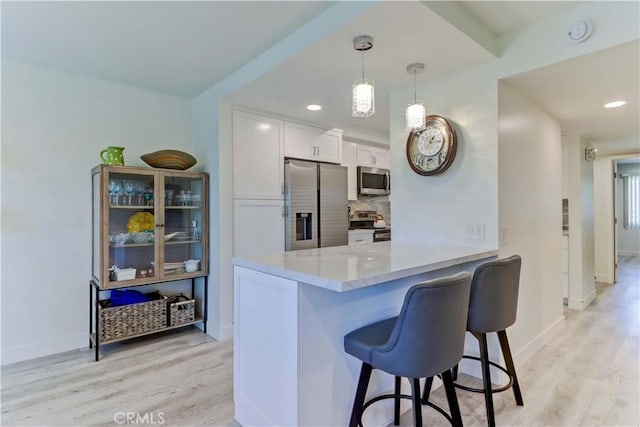 3365 Punta Alta Unit 2F, Laguna Woods, CA 92637 - kitchen featuring appliances with stainless steel finishes, a kitchen bar, light wood-style flooring, white cabinets, and recessed lighting