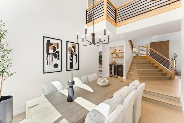 24876 Avenida Avalon, Laguna Hills, CA 92653 - dining room featuring wine cooler, stairway, light wood finished floors, a towering ceiling, and a chandelier