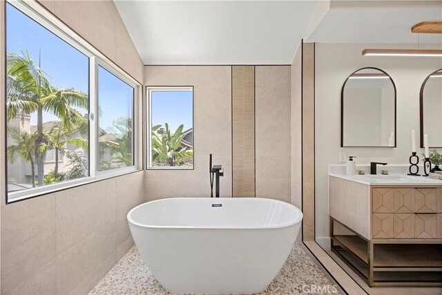 24876 Avenida Avalon, Laguna Hills, CA 92653 - full bathroom featuring a freestanding bath, vanity, plenty of natural light, tile walls, and vaulted ceiling