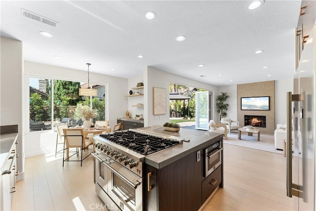 24876 Avenida Avalon, Laguna Hills, CA 92653 - kitchen with range with two ovens, dark brown cabinets, recessed lighting, a kitchen island, and a fireplace