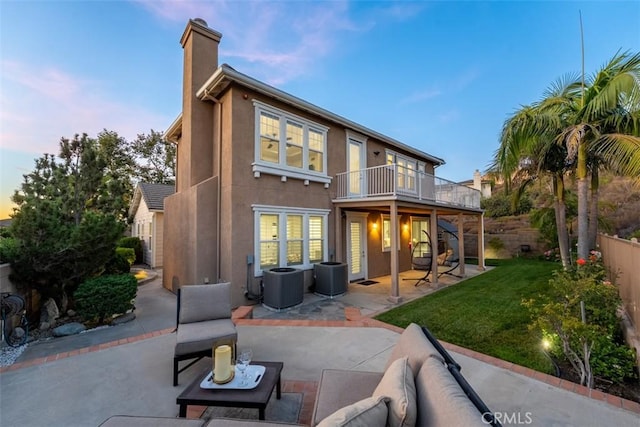 2886 Muir Trail Dr, Fullerton, CA 92833 - back of house at dusk with a patio, a chimney, stucco siding, a balcony, and outdoor lounge area