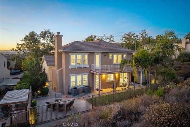 2886 Muir Trail Dr, Fullerton, CA 92833 - back of property at dusk featuring a patio area, stucco siding, a fenced backyard, a chimney, and a balcony