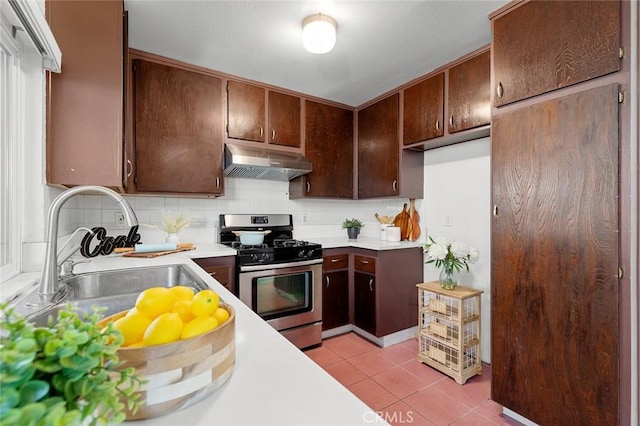 8515 Edgebrook Dr, Garden Grove, CA 92844 - kitchen with stainless steel gas stove, under cabinet range hood, light tile patterned flooring, light countertops, and backsplash