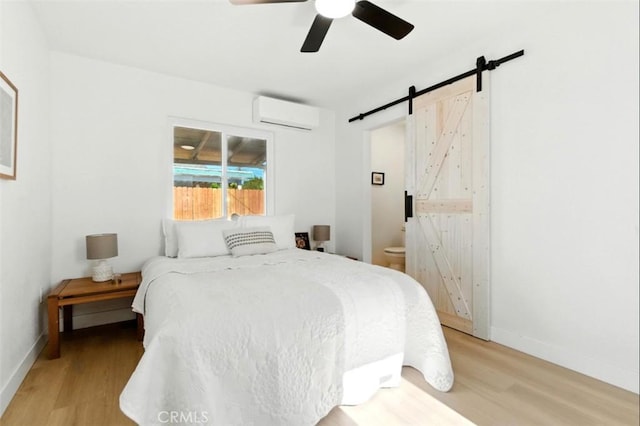 3839 Riverside Dr, Chino, CA 91710 - bedroom with light wood-type flooring, a barn door, a wall mounted AC, and a ceiling fan