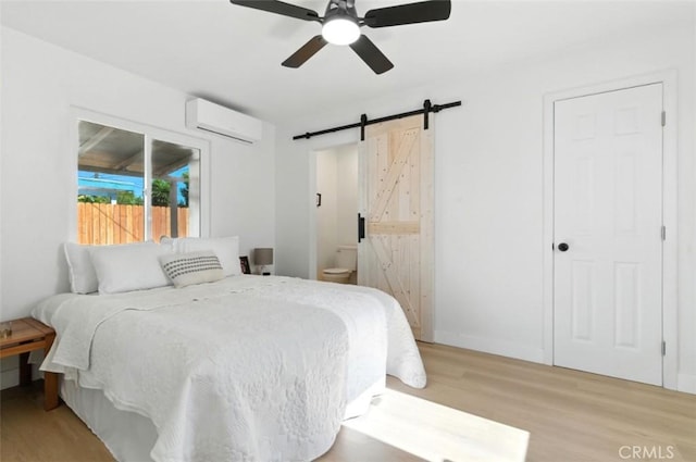 3839 Riverside Dr, Chino, CA 91710 - bedroom featuring a wall mounted air conditioner, light wood-style floors, a barn door, connected bathroom, and a ceiling fan