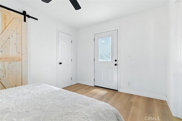 3839 Riverside Dr, Chino, CA 91710 - bedroom with a barn door, light wood-type flooring, and a ceiling fan