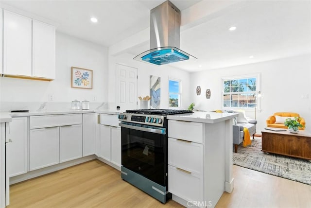 3839 Riverside Dr, Chino, CA 91710 - kitchen featuring stainless steel range with gas cooktop, island exhaust hood, a peninsula, light wood finished floors, and light countertops
