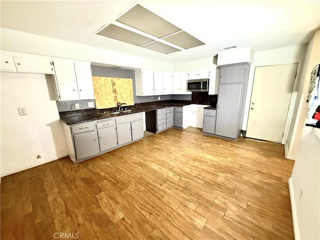 24423 Dunlavy Ct, Moreno Valley, CA 92557 - kitchen featuring stainless steel microwave, dark countertops, light wood-style floors, and white cabinetry