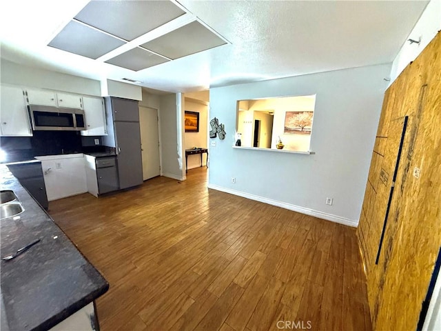 24423 Dunlavy Ct, Moreno Valley, CA 92557 - kitchen featuring stainless steel microwave, wood finished floors, white cabinets, and dark countertops