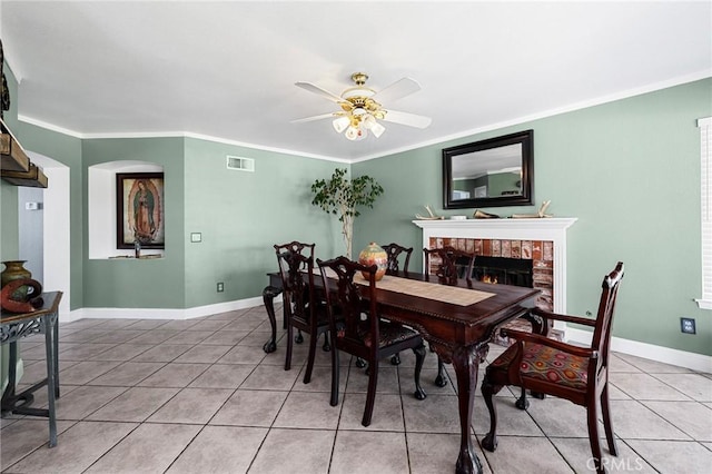 3143 Tourmaline Ln, Palmdale, CA 93550 - dining room featuring light tile patterned floors, a ceiling fan, a fireplace, and ornamental molding
