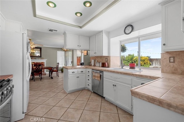 3143 Tourmaline Ln, Palmdale, CA 93550 - kitchen featuring appliances with stainless steel finishes, a peninsula, light tile patterned flooring, decorative backsplash, and white cabinets