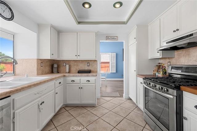 3143 Tourmaline Ln, Palmdale, CA 93550 - kitchen with stainless steel appliances, under cabinet range hood, a tray ceiling, white cabinetry, and backsplash