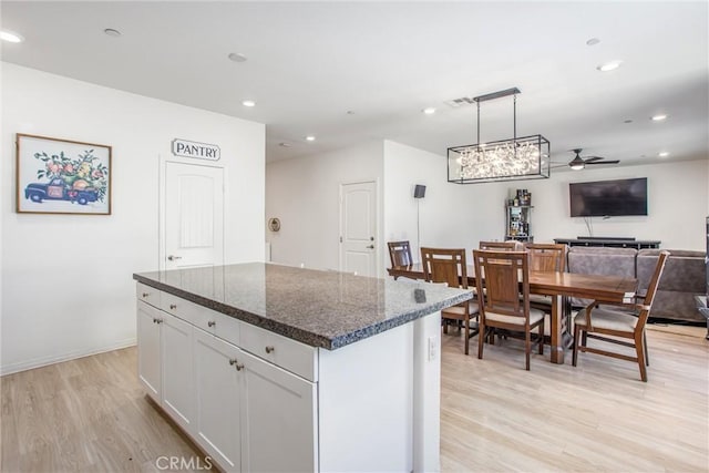 1180 Little Leaf, Calimesa, CA 92320 - kitchen with light wood finished floors, a kitchen island, a ceiling fan, dark stone countertops, and open floor plan