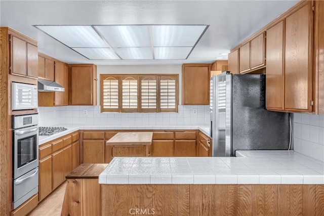 2433 S Gaffey St, San Pedro, CA 90731 - kitchen featuring appliances with stainless steel finishes, a warming drawer, decorative backsplash, and light countertops