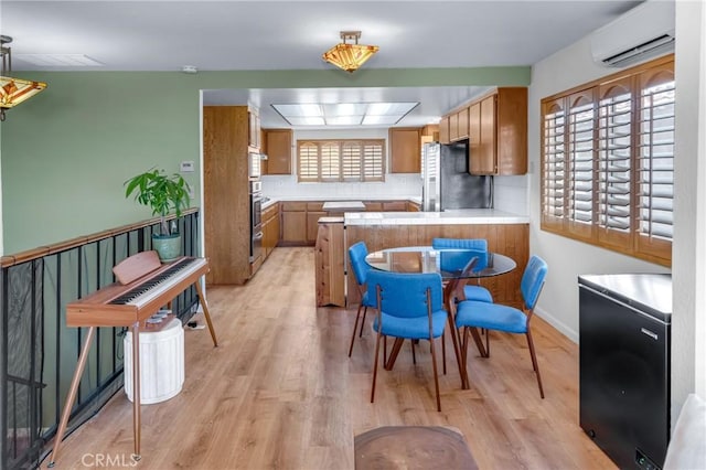 2433 S Gaffey St, San Pedro, CA 90731 - kitchen with stainless steel appliances, a wall mounted AC, brown cabinets, and light wood finished floors