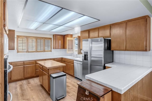2433 S Gaffey St, San Pedro, CA 90731 - kitchen featuring appliances with stainless steel finishes, backsplash, a peninsula, a center island, and light wood-style floors