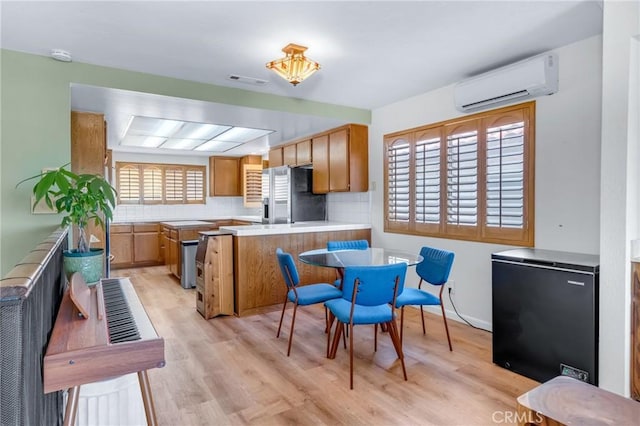 2433 S Gaffey St, San Pedro, CA 90731 - kitchen featuring stainless steel refrigerator with ice dispenser, black refrigerator, an AC wall unit, a peninsula, and light wood-style flooring