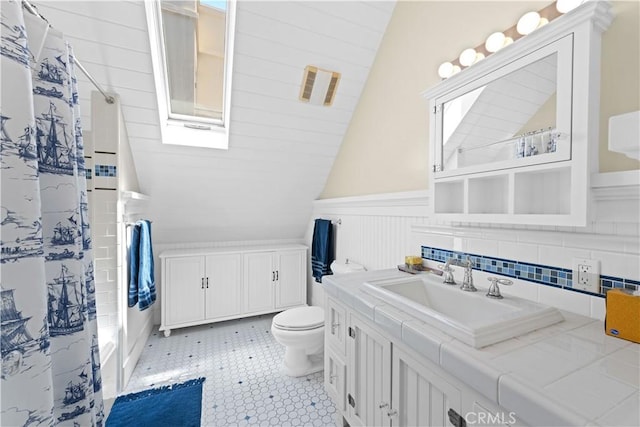 6025 E Ocean Blvd, Long Beach, CA 90803 - bathroom featuring lofted ceiling, vanity, curtained shower, wainscoting, and a skylight