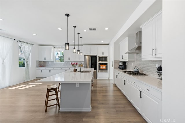 32084 Richardson St, Menifee, CA 92584 - kitchen featuring wall chimney range hood, stainless steel appliances, wood finished floors, decorative backsplash, and light countertops