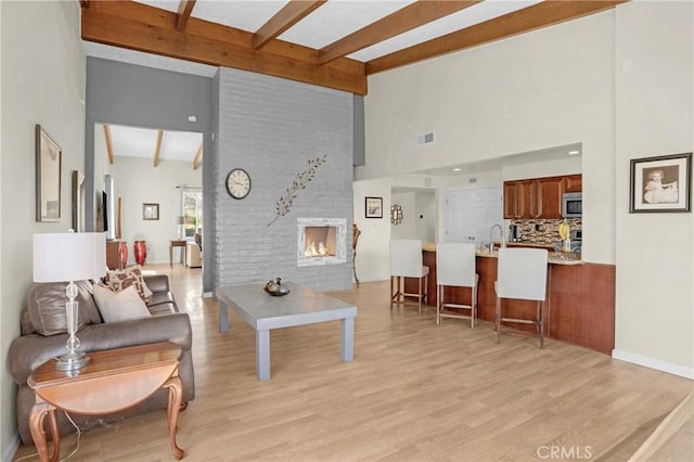 12674 Metate Ln, Poway, CA 92064 - living room featuring beam ceiling, a large fireplace, light wood finished floors, and high vaulted ceiling