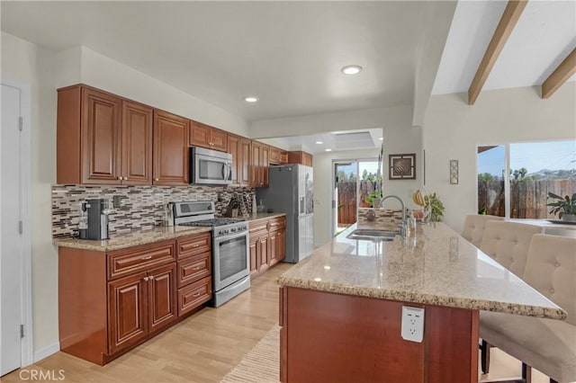 12674 Metate Ln, Poway, CA 92064 - kitchen featuring stainless steel appliances, light wood-style flooring, a breakfast bar area, decorative backsplash, and light stone countertops