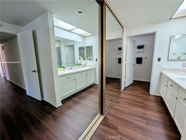 5499 Paseo Del Lago W Unit 3D, Laguna Woods, CA 92637 - bathroom with a skylight, wood finished floors, a textured ceiling, and two vanities