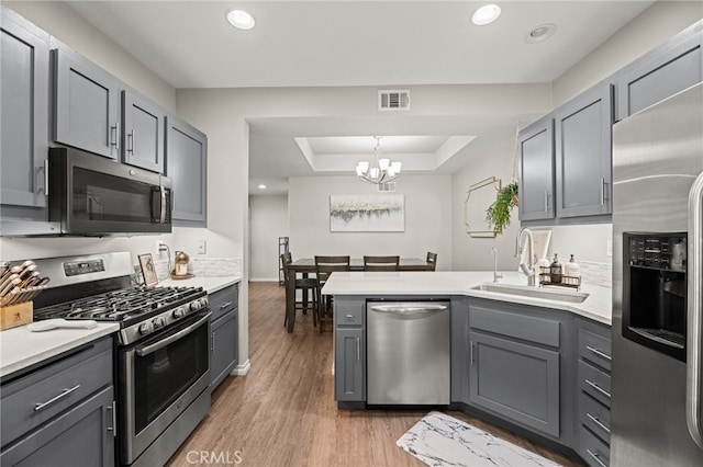 3732 Calle Monada, Riverside, CA 92503 - kitchen with stainless steel appliances, gray cabinetry, a raised ceiling, a peninsula, and a chandelier