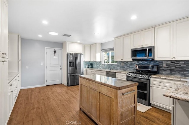 7985 Stella St, Riverside, CA 92504 - kitchen with stainless steel appliances, a center island, decorative backsplash, and light wood-style flooring