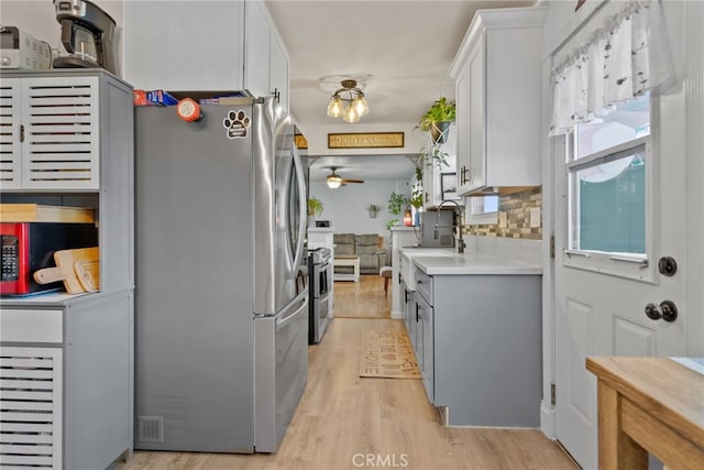 7430 Dunkirk Ave, Highland, CA 92346 - kitchen featuring stainless steel appliances, light countertops, a ceiling fan, light wood-type flooring, and backsplash