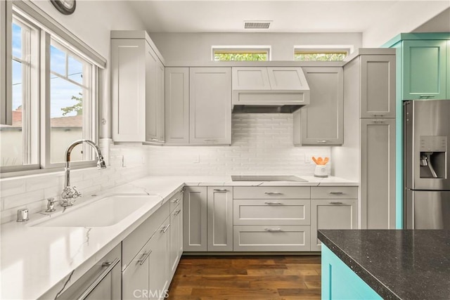 6557 Clybourn Ave, North Hollywood, CA 91606 - kitchen with stainless steel fridge with ice dispenser, custom exhaust hood, black electric stovetop, and tasteful backsplash