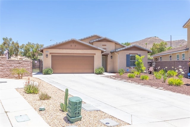 29184 Tree House, Lake Elsinore, CA 92530 - view of front of property with driveway, a garage, stucco siding, a gate, and a mountain view