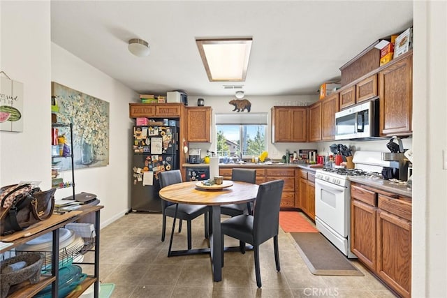 1654 E Ave, Chico, CA 95926 - kitchen with stainless steel microwave, freestanding refrigerator, white gas range oven, and brown cabinetry