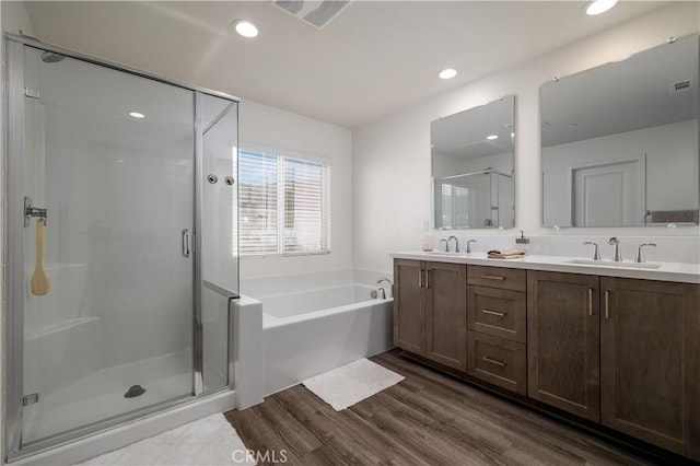 29526 Woodcreek Trl, Winchester, CA 92596 - bathroom featuring a stall shower, double vanity, a bath, wood finished floors, and recessed lighting