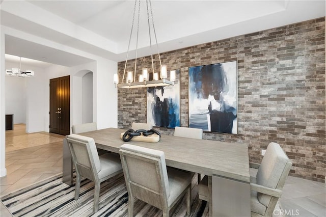 41783 Valencia Way, Temecula, CA 92592 - dining area with a chandelier, a tray ceiling, arched walkways, light tile patterned floors, and an accent wall
