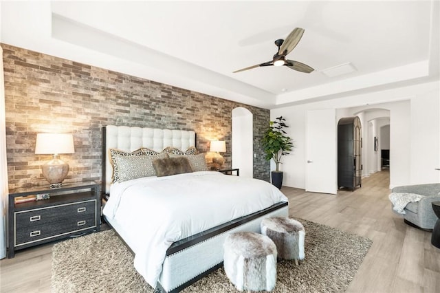 41783 Valencia Way, Temecula, CA 92592 - bedroom featuring a tray ceiling, arched walkways, light wood-style flooring, and ceiling fan