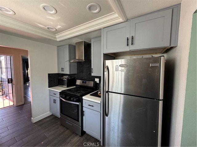 825 E Eagle St, Long Beach, CA 90806 - kitchen with stainless steel appliances, wall chimney exhaust hood, a tray ceiling, light countertops, and dark wood-style flooring