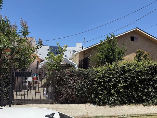 1569 E 109th St, Los Angeles, CA 90059 - view of side of property featuring stucco siding and a gate