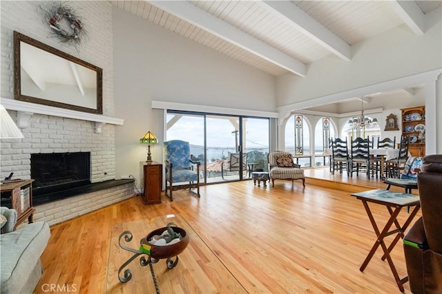 750 Luisita St, Morro Bay, CA 93442 - living area featuring high vaulted ceiling, beam ceiling, wood finished floors, a brick fireplace, and a chandelier