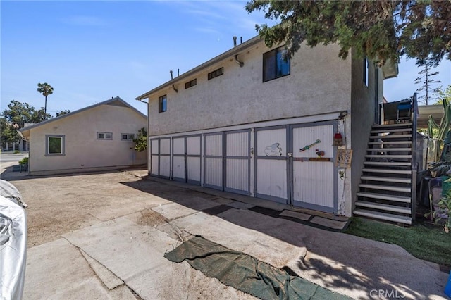 228 S 4th St, Santa Paula, CA 93060 - rear view of house featuring stairs, driveway, an attached garage, and stucco siding