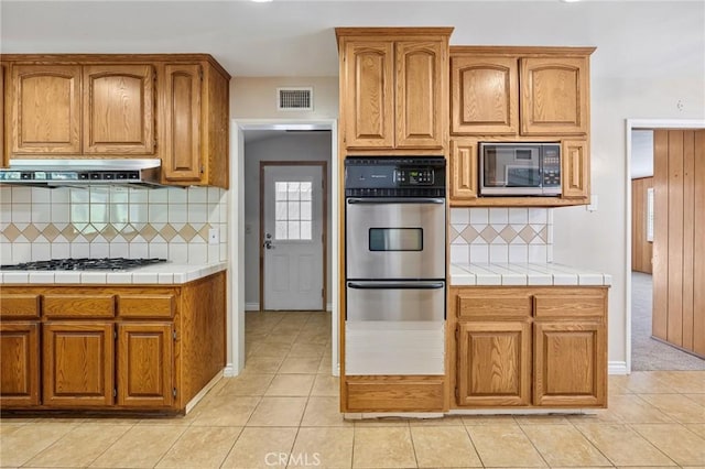 1296 Tiger Tail Dr, Riverside, CA 92506 - kitchen with appliances with stainless steel finishes, a warming drawer, tasteful backsplash, extractor fan, and light tile patterned floors
