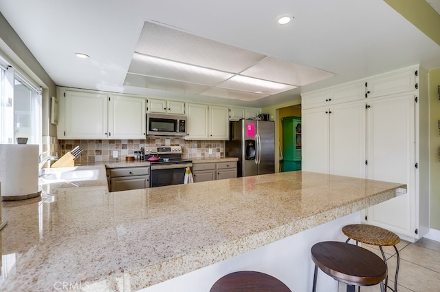 23402 Devonshire Dr, Lake Forest, CA 92630 - kitchen featuring appliances with stainless steel finishes, a peninsula, backsplash, a kitchen breakfast bar, and recessed lighting