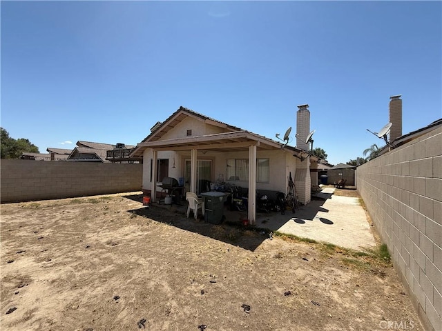 5320 Jonah St, Bakersfield, CA 93307 - rear view of house with a fenced backyard, a patio, stucco siding, and a chimney