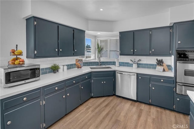 9811 Kempster Ave, Fontana, CA 92335 - kitchen featuring appliances with stainless steel finishes, a warming drawer, decorative backsplash, light wood-style floors, and light countertops