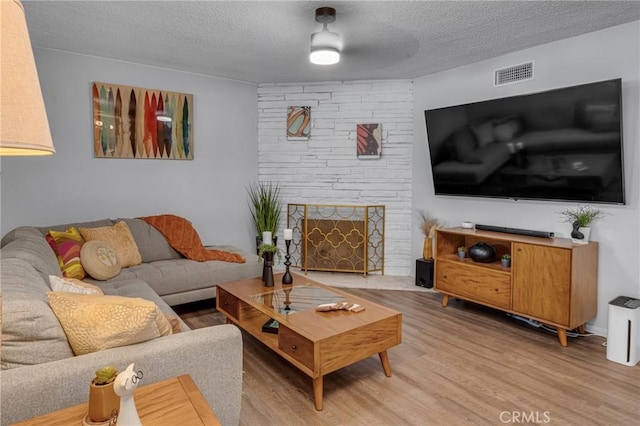 9811 Kempster Ave, Fontana, CA 92335 - living area with light wood-type flooring, a textured ceiling, and a fireplace